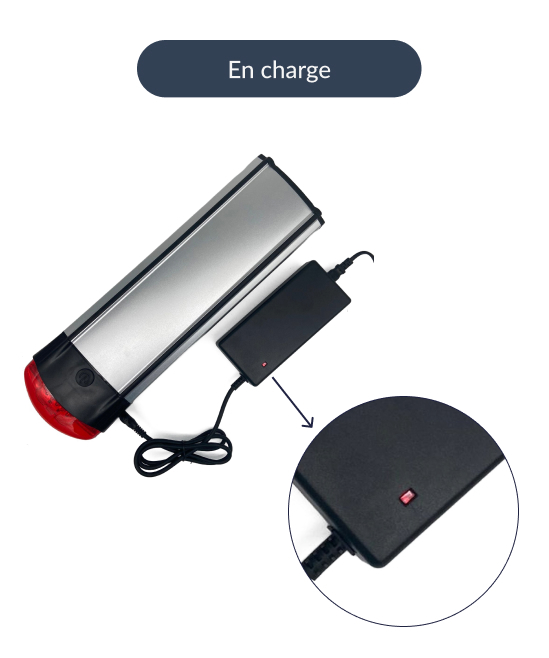 Cette image montre une batterie de vélo Stella avec le chargeur connecté. La batterie est en cours de chargement, le voyant du chargeur est rouge.