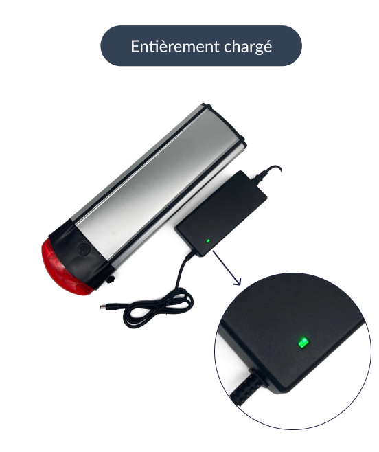 Cette image montre une batterie de vélo Stella avec le chargeur correspondant. Ce chargeur est prêt à charger la batterie. La lumière sur le chargeur est verte.